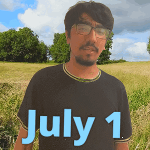 a man wearing glasses stands in a field with the date july 1 on his shirt