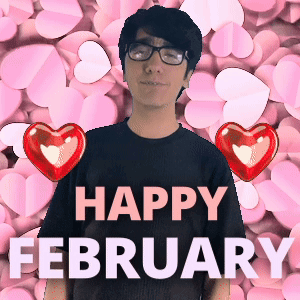A Man Wearing Glasses Stands In Front Of A Background Of Pink Hearts And The Words Happy February GIF