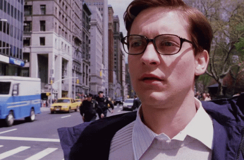 A Man Wearing Glasses Stands In Front Of A Blue And White Police Truck GIF