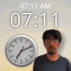 A Man Wearing Glasses Stands In Front Of A Clock That Reads 7:11 Am GIF