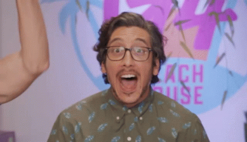 A Man Wearing Glasses Stands In Front Of A Peach House Sign GIF
