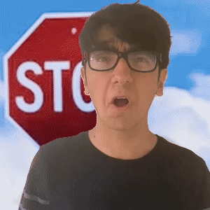 A Man Wearing Glasses Stands In Front Of A Red Stop Sign GIF