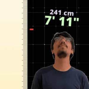 A Man Wearing Glasses Stands In Front Of A Ruler That Says 241 Cm 7'11 " GIF