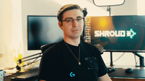 A Man Wearing Glasses Stands In Front Of A Shroud Sign GIF