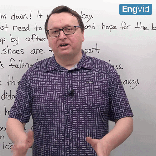 a man wearing glasses stands in front of a whiteboard that says " kay " on it