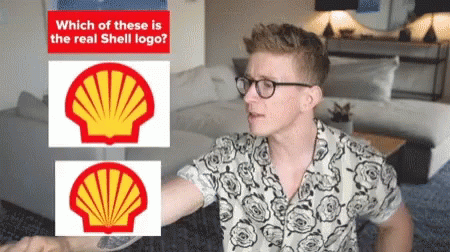A Man Wearing Glasses Stands In Front Of Two Shell Logos GIF
