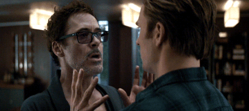 A Man Wearing Glasses Talks To Another Man In A Room GIF