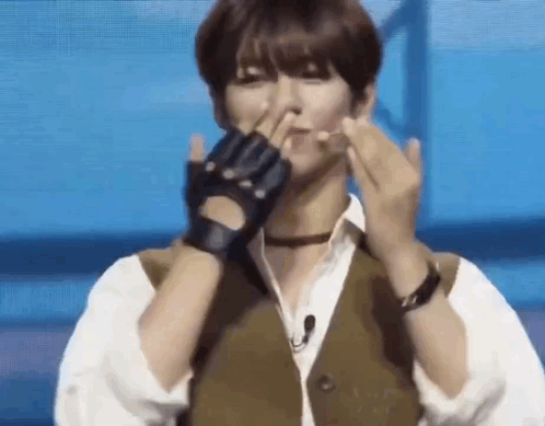 A Man Wearing Gloves And A Vest Is Making A Heart With His Hands . GIF