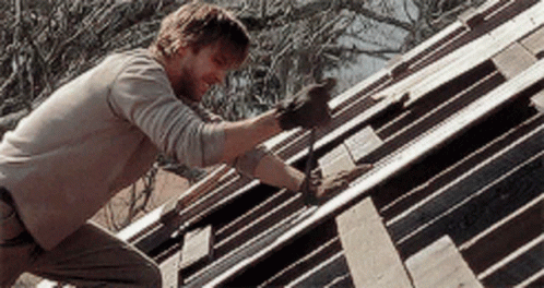 A Man Wearing Gloves Is Working On A Wooden Roof GIF