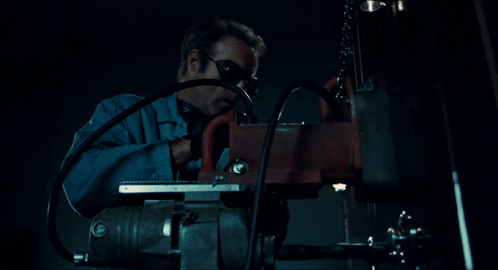 A Man Wearing Goggles Is Using A Machine In The Dark GIF