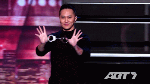 A Man Wearing Handcuffs Stands On A Stage In Front Of An Agt 7 Logo GIF