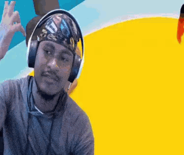 A Man Wearing Headphones And A Bandana Is Giving A Peace Sign . GIF