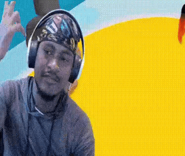 a man wearing headphones and a bandana on his head is making a peace sign