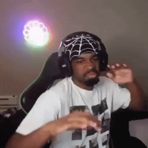 A Man Wearing Headphones And A Bandana With A Spider Web On It Is Sitting In A Chair . GIF