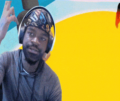 A Man Wearing Headphones And A Bandana With The Letter T On It Is Giving A Peace Sign GIF