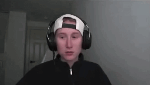 a man wearing headphones and a baseball cap is looking at the camera .