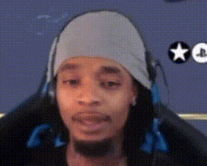 A Man Wearing Headphones And A Beanie Is Sitting In A Chair . GIF