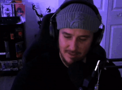 A Man Wearing Headphones And A Beanie Says " Ayy Man " In Red GIF