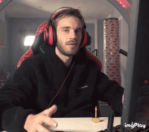A Man Wearing Headphones And A Black Columbia Jacket Sitting At A Desk GIF
