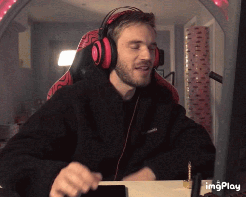 A Man Wearing Headphones And A Black Columbia Sweatshirt Is Sitting At A Desk GIF