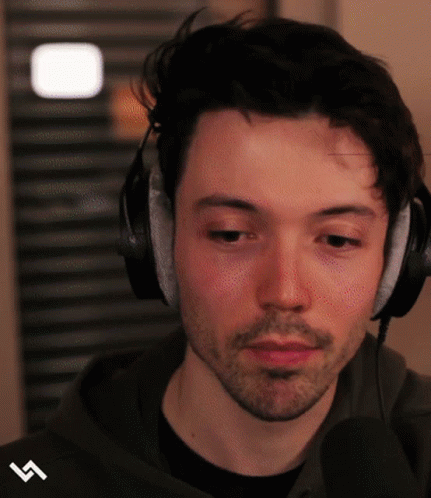 A Man Wearing Headphones And A Black Shirt Has The Letter S On His Sleeve GIF