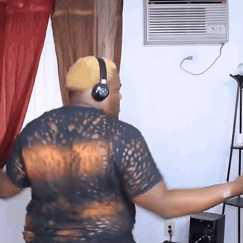 a man wearing headphones and a black shirt is dancing in a living room
