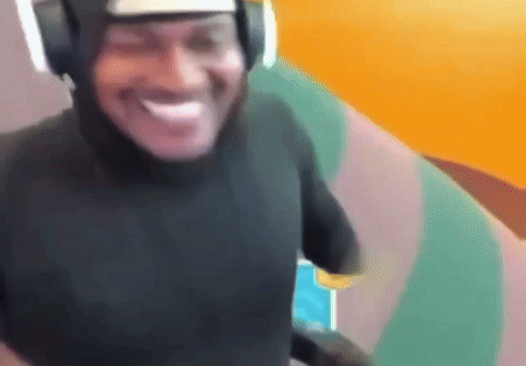 A Man Wearing Headphones And A Black Shirt Is Smiling And Looking At The Camera . GIF