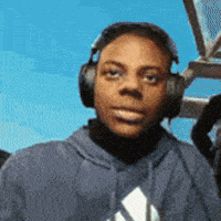 a man wearing headphones and a blue adidas hoodie looks at the camera