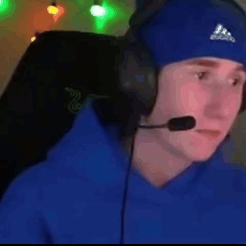 a man wearing headphones and a blue hat is sitting in a chair .