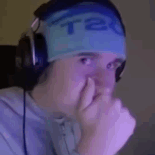 a man wearing headphones and a blue headband is covering his nose with his hand .