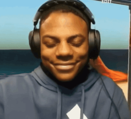 a man wearing headphones and a blue hoodie smiles