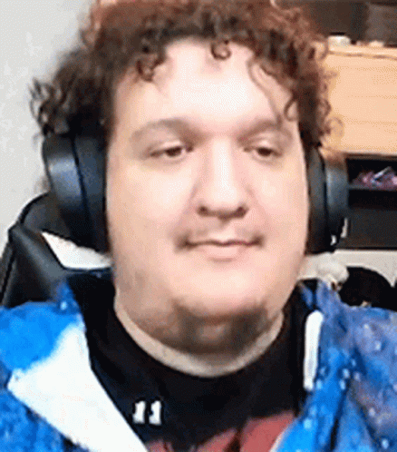 A Man Wearing Headphones And A Blue Jacket Is Sitting In Front Of A Computer . GIF