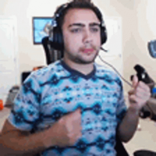 A Man Wearing Headphones And A Blue Shirt Is Holding A Controller In His Hand . GIF