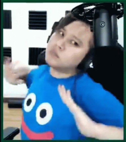 A Man Wearing Headphones And A Blue Shirt With A Smiley Face On It Is Sitting In A Chair . GIF