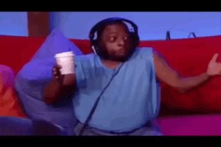 A Man Wearing Headphones And A Blue Tank Top Is Sitting On A Couch Holding A Cup Of Coffee . GIF