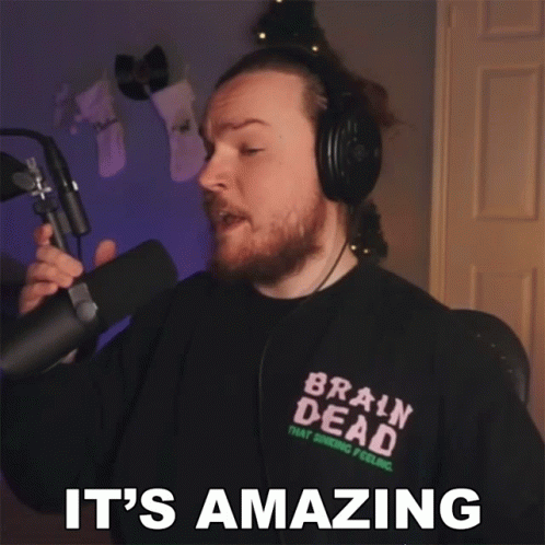 A Man Wearing Headphones And A Brain Dead Shirt Is Holding A Microphone And Says It 'S Amazing GIF