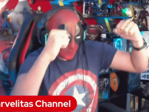 A Man Wearing Headphones And A Captain America Shirt Is Dancing In Front Of A Marvelitas Channel Sign GIF