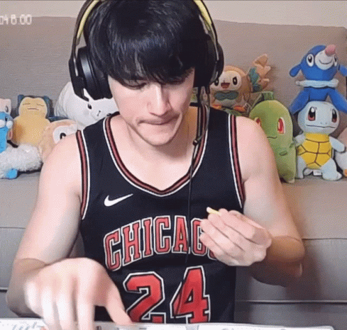 A Man Wearing Headphones And A Chicago 24 Jersey Eating A Snack GIF