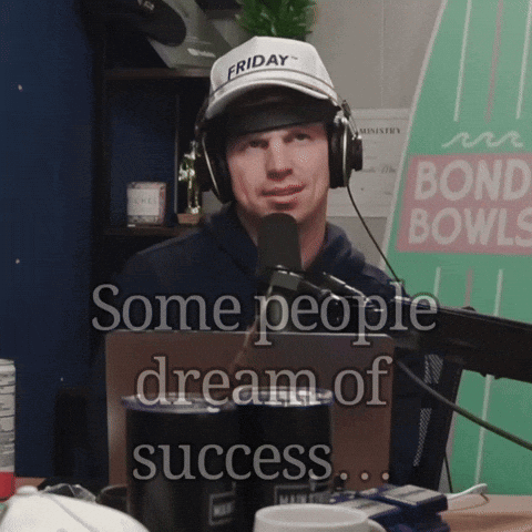 A Man Wearing Headphones And A Friday Hat Is Talking Into A Microphone GIF