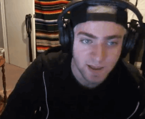 a man wearing headphones and a hat is looking at the camera .