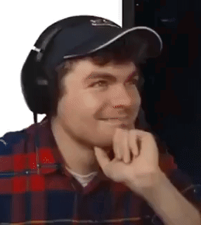 A Man Wearing Headphones And A Hat Is Making A Face . GIF