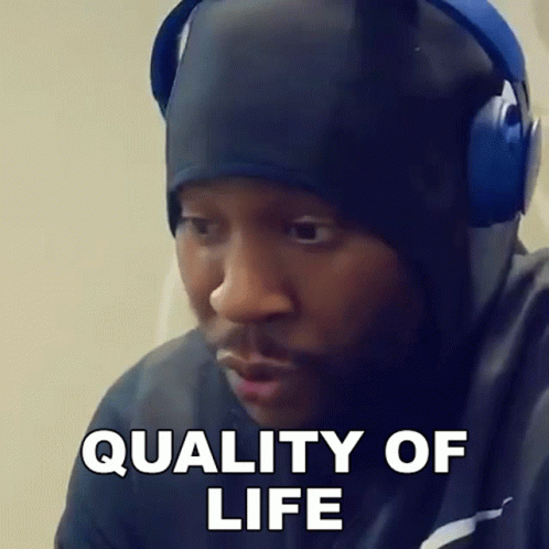 A Man Wearing Headphones And A Hat Is Making A Funny Face And Saying Quality Of Life . GIF