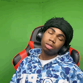 A Man Wearing Headphones And A Hat Is Sitting In A Chair . GIF