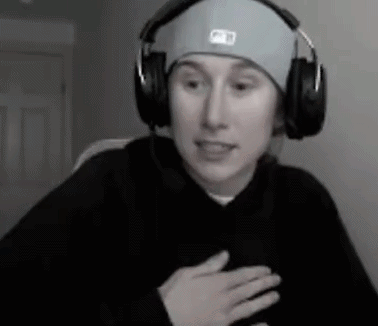 a man wearing headphones and a hat is sitting in front of a computer .