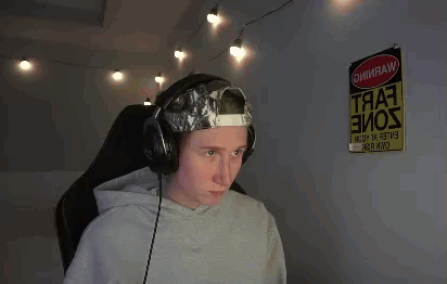 a man wearing headphones and a hat is sitting in front of a computer .