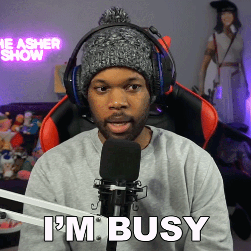 A Man Wearing Headphones And A Hat Says I 'M Busy In Front Of A Microphone GIF