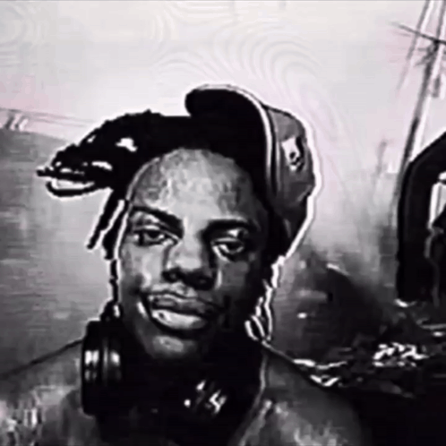 A Man Wearing Headphones And A Hat With A Skull On It GIF