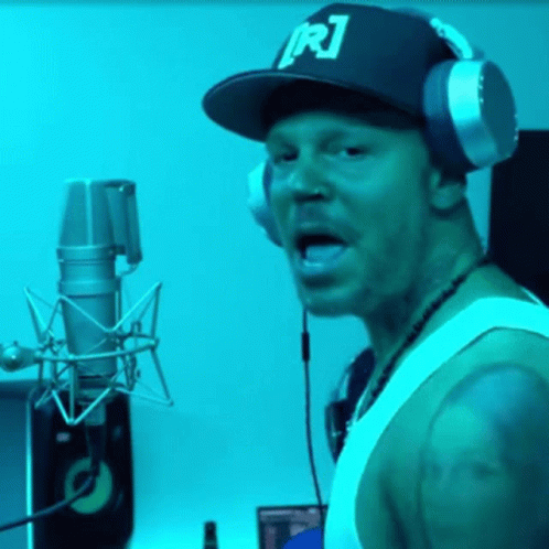 A Man Wearing Headphones And A Hat With R1 On It GIF