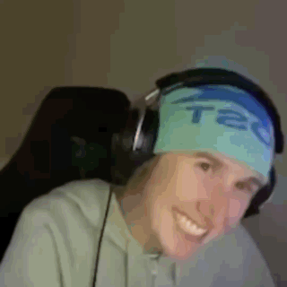a man wearing headphones and a headband that says tec is smiling .