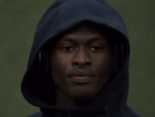A Man Wearing Headphones And A Hooded Jacket Looks At The Camera GIF